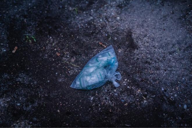 een boterhamzak met daarin veel drugszakjes op de grond